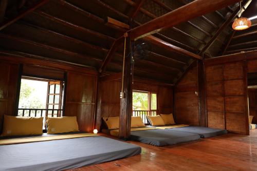 two beds in a room with wooden ceilings and windows at 6Senses Garden Homestay in Hòa Bình