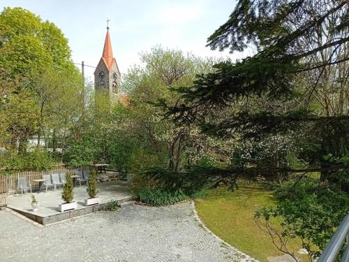 a view of a garden with a church in the background at Gasthof-Pension Zum Haugstein - Familie Eder in Engelhartszell