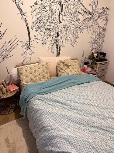 a bedroom with a bed with a blue and white comforter at Maison à proximité du circuit 24h in Saint-Gervais en-Belin