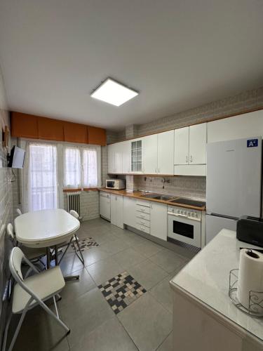 cocina con armarios blancos, mesa y mesa en Apartamento en el Centro Histórico de Nájera en Nájera