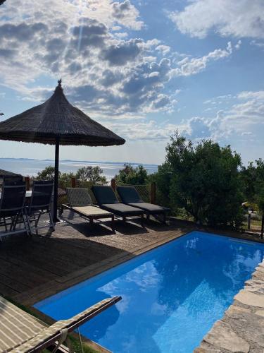 a pool with chairs and an umbrella and a table and chairs at Golden Haven Luxe Bungalow Resort in Murter