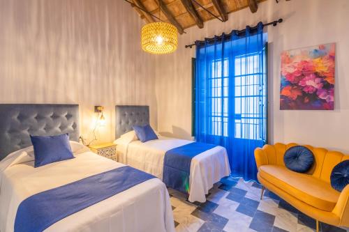 1 dormitorio con 2 camas, sofá y ventana en AL-QUIVIR Suites, en Córdoba
