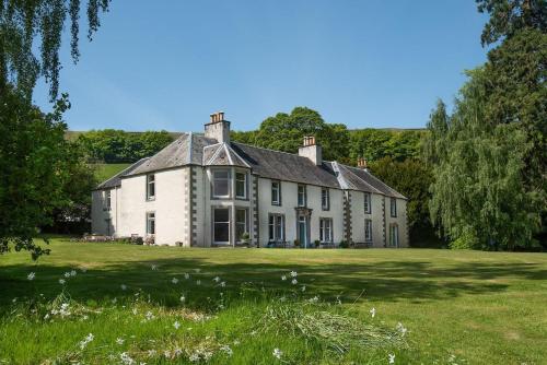 a large white house on a green field at Mossfennan House & Annexe in Drummelzier