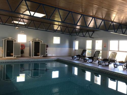 a large swimming pool with chairs and tables in a building at Brixham Holiday Park Silver Albatross - Pet Friendly in Brixham