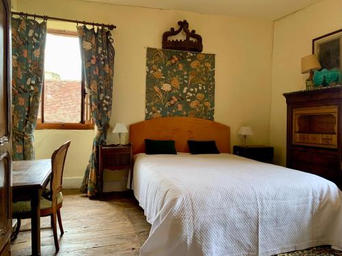 Schlafzimmer mit einem Bett, einem Tisch und einem Fenster in der Unterkunft Maison du Chapitre in Prudhomat