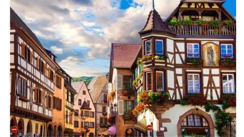 un vieux bâtiment avec des boîtes de fleurs dans une ville dans l'établissement Appartements & Chambres Les Loges du Capucin, à Kaysersberg