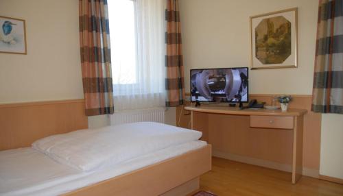 a bedroom with a bed and a tv on a desk at Hotel Garni Grottental in Meßstetten