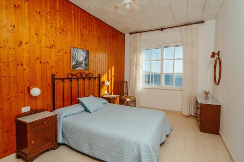 1 dormitorio con 1 cama y pared de madera en Apartamentos Ancoradoiro en Lariño