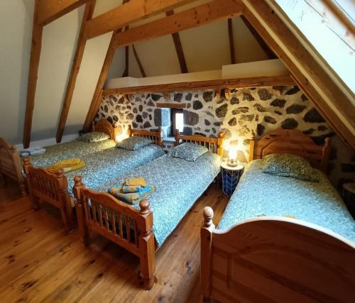 an attic with three beds in a room at Gite tout confort 10 pers à 8 km du Lioran in Saint-Jacques-des-Blats