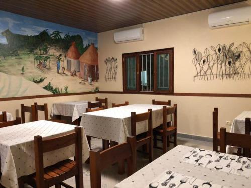 Hotel Bom Amigo في إنهامبان: مطعم بطاولات وكراسي و لوحة على الحائط