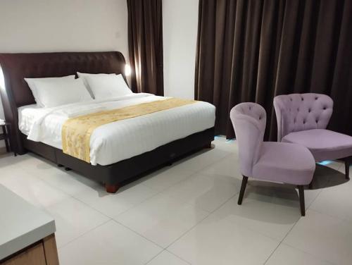 a bedroom with a bed and a purple chair at BIG TREE HOTEL in Temerloh