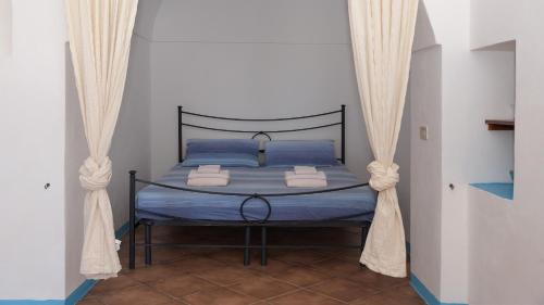 1 dormitorio con 1 cama con sábanas y cortinas azules en Lighted Pool, Barbecue & Sea View - Authentic "Dammusi" en Pantelleria