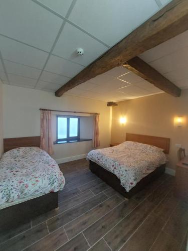 a bedroom with two beds and a window at Padley Farm in Bradfield