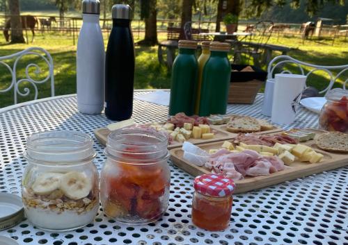 a table with a plate of food and jars of food at La Roulotte deluxe de Malpas in Quingey
