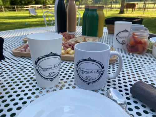 a table with two coffee cups and a plate of food at La Roulotte deluxe de Malpas in Quingey