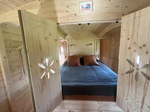 a bedroom with a bed in a wooden cabin at La Roulotte deluxe de Malpas in Quingey