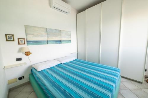 1 dormitorio blanco con 1 cama con sábanas azules en La Gabbiana, en Portoferraio
