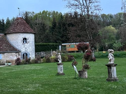 a yard with statues in front of a building at La Roulotte deluxe de Malpas in Quingey