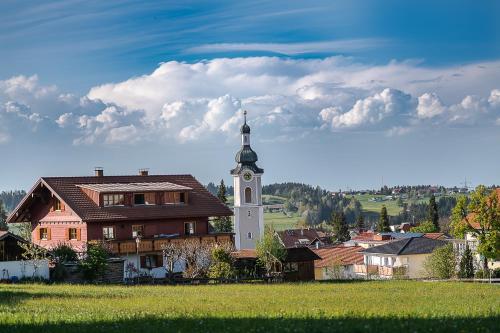 a building with a clock tower next to a house at Scheidegg unterm Kreuzberg in Scheidegg