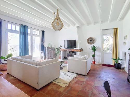 a living room with two white couches and a tv at Le Relais de Fleyres - Gîte Authentique avec Jardin, Parking et Wifi in Toulouse