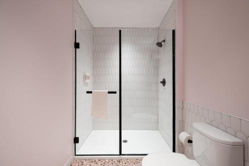 a white bathroom with a shower with a toilet at The Neighborhood Hotel - Little Italy Studio in Chicago