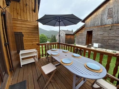 un tavolo blu e sedie su una terrazza con ombrellone di Chalet le Brespail a Boutx