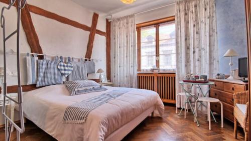 a bedroom with a bed and a desk and a window at Appartements & Chambres Les Loges du Capucin in Kaysersberg