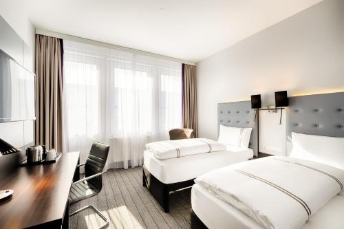 una camera d'albergo con due letti e una scrivania di Premier Inn München City Ost a Monaco