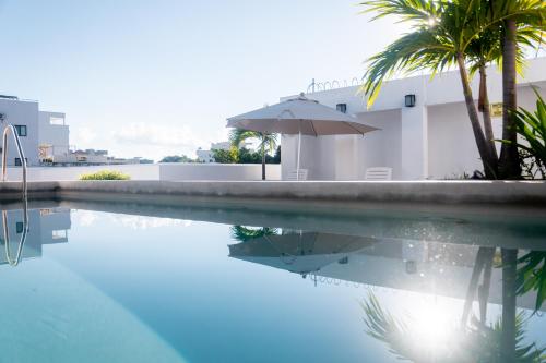 a swimming pool with an umbrella next to a building at Arkana 9 Suites by Grupo Amber in Playa del Carmen