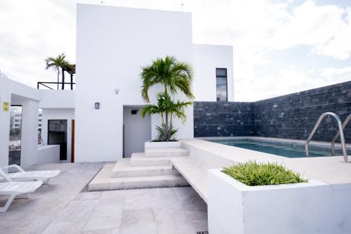 un patio con piscina y palmeras en una casa en Arkana 9 Suites Grupo Amber - Collection O en Playa del Carmen