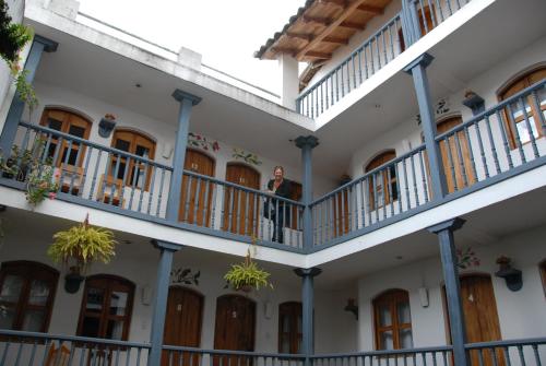 a man stands on the balcony of a building at Hotel Doña Esther in Otavalo