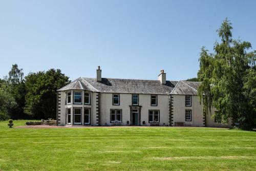 a large house with a large grassy yard at Mossfennan House in Drummelzier