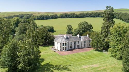 an aerial view of a large house in a field at Mossfennan House in Drummelzier