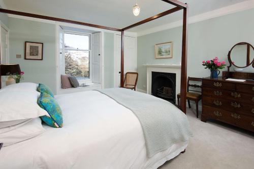 a bedroom with a large white bed and a fireplace at Mossfennan House in Drummelzier
