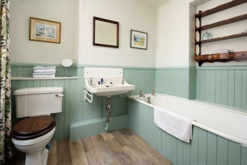a bathroom with a toilet and a sink and a bath tub at Mossfennan House in Drummelzier