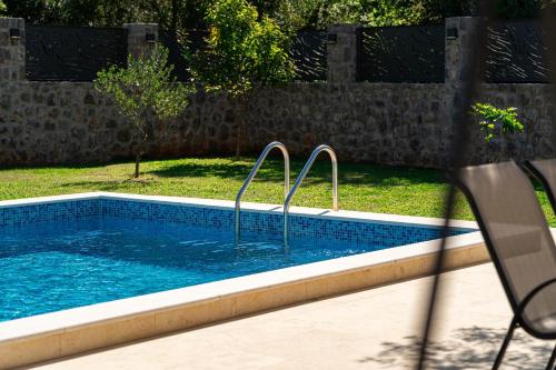 a swimming pool with two metal rails in a yard at Villa Stemi in Tivat