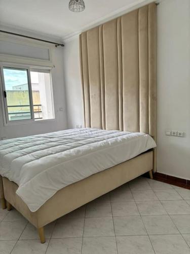 un grande letto in una camera da letto con finestra di Appartement lumineux et moderne sur Mohammedia a Mohammedia
