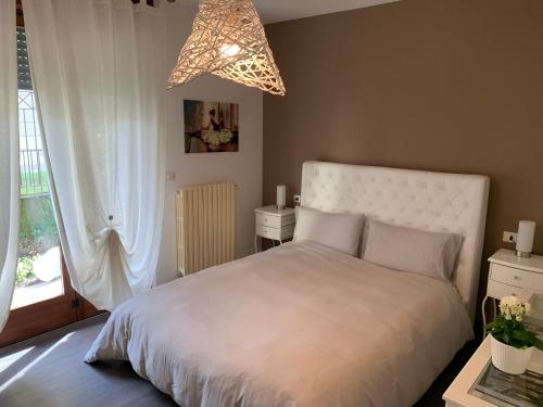 una camera con letto bianco e lampadario pendente di Xenia di Giò - Appartamento con giardino a Caravaggio