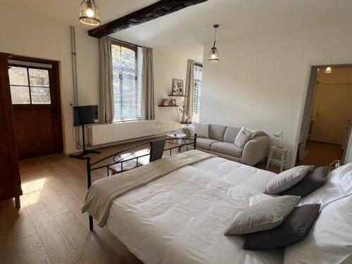 a bedroom with a large white bed and a couch at B&B Sjaanderhof in Maastricht