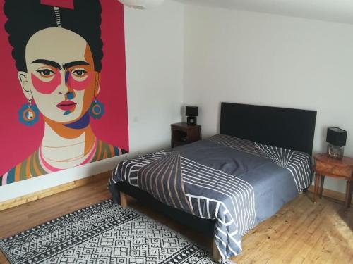 - une chambre avec un lit orné d'une peinture de femme dans l'établissement Maison dans la baie du Mont St Michel, à Genêts