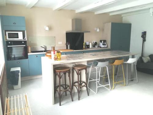 une cuisine avec un grand comptoir et des tabourets dans l'établissement Maison dans la baie du Mont St Michel, à Genêts