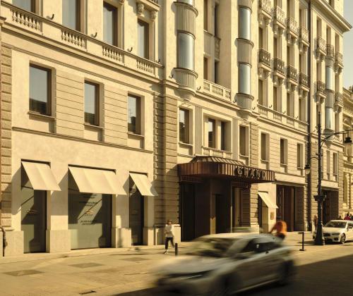 samochód jadący ulicą przed budynkiem w obiekcie Grand Hotel w Łodzi