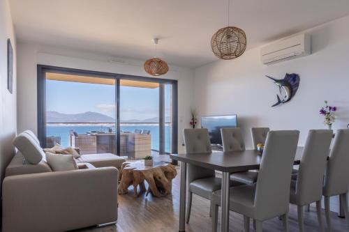 une salle à manger avec une table et des chaises et un chien dans l'établissement Les Terrasses de l'Isolella - Vue mer et montagne, à Pietrosella