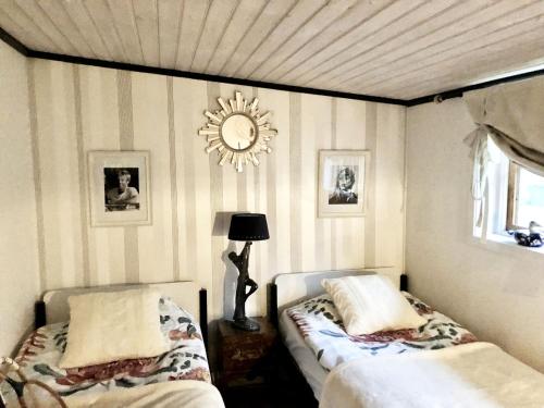 1 dormitorio con 2 camas y reloj en la pared en Pleasant accommodation with its own beach located along the Jungfrukusten, en Bergby