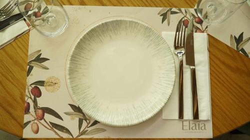 a white plate on a table with a fork and knife at Magnes Hotel in Volos