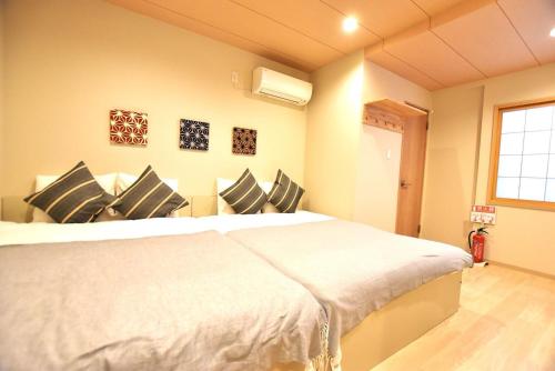1 dormitorio con 1 cama blanca grande con almohadas negras en Tamatsukan 玉津館, Detached Hse, JR Tsuruhashi 7min, Kansai Airport 關西空港 57 mins, Namba 6 mins, Nihonbashi 4 mins, Universal Studio 37 mins, Nara 30 mins, Early Check In, en Osaka