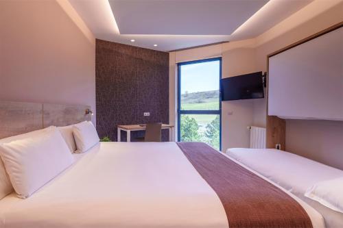 a bedroom with a large bed and a large window at Spirit Hotel Ciudad de Burgos in Rubena