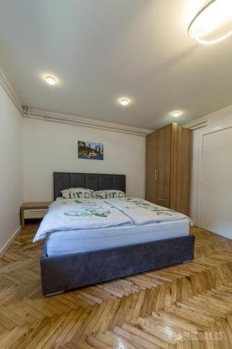 um quarto com uma cama grande e piso em madeira em BB Sima 1 em Bajina Bašta
