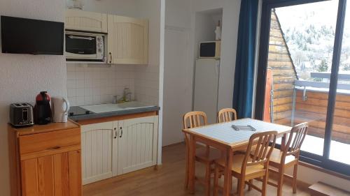 a kitchen with a table and chairs and a kitchen with a window at appartement chaleureux avec terrasse ensoleillée 2 étoiles in Le Mont-Dore