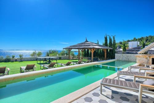 a swimming pool with chairs and a gazebo at Golden Haven in Murter
